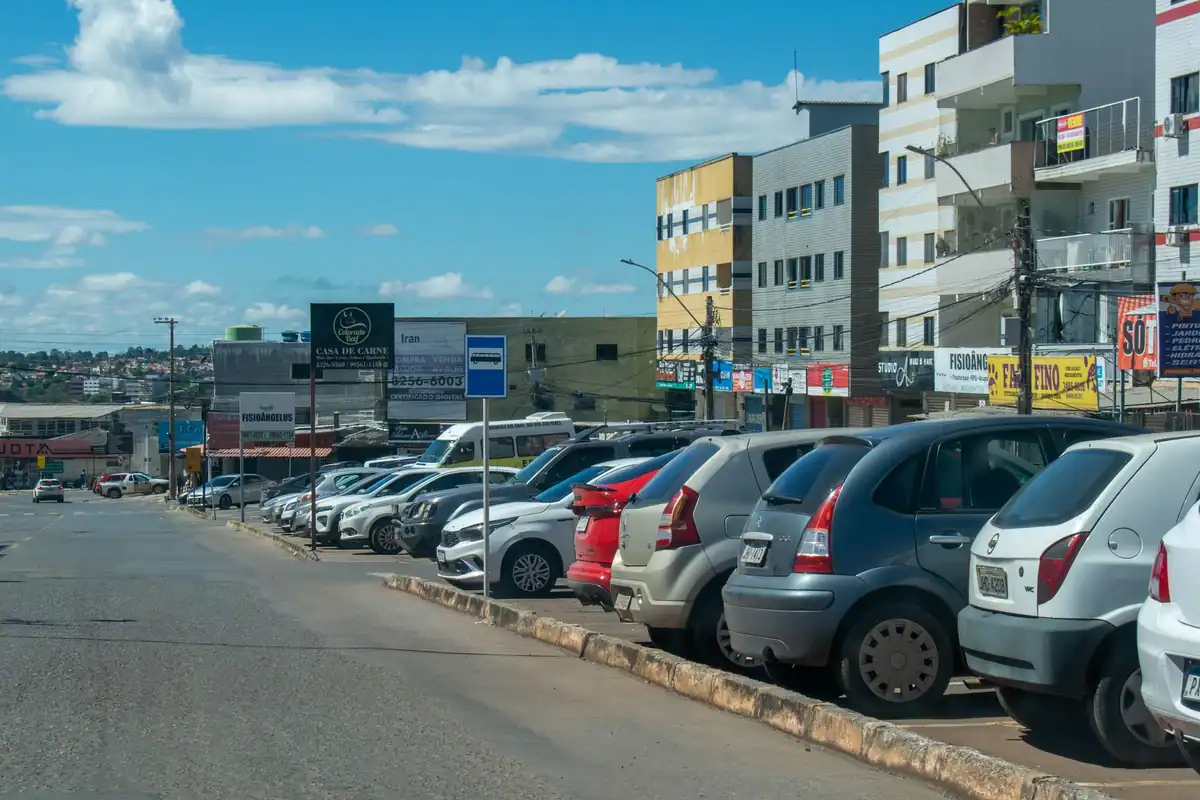 Mașini parcate la rând pe marginea unei străzi dintr-un oraș însorit