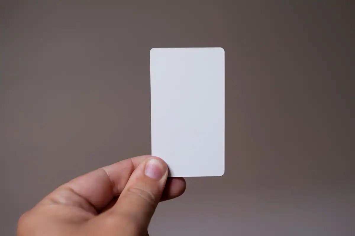 Mână care ține un card alb din plastic, fără nicio inscripție