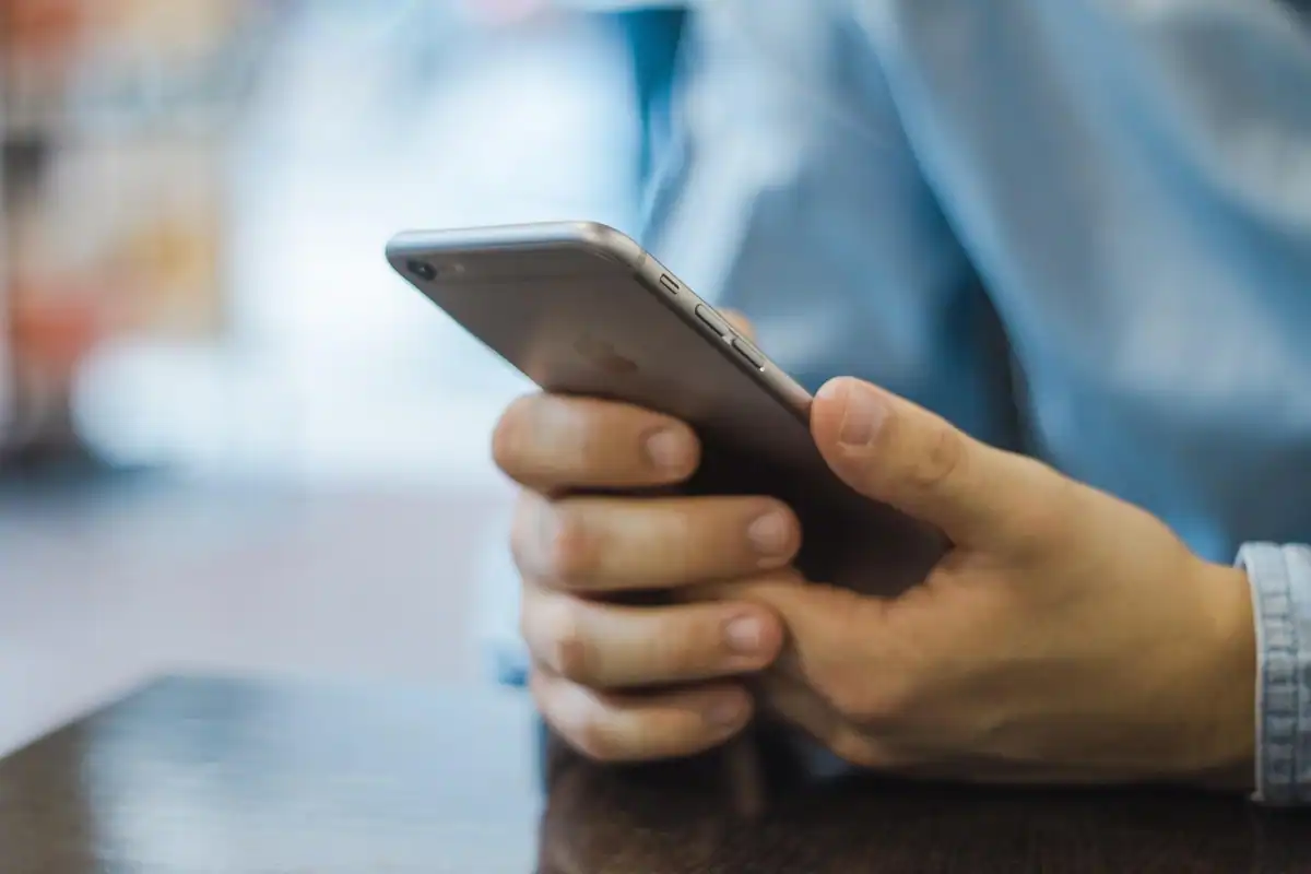 Mâini care țin un telefon mobil, pentru accesarea serviciilor online