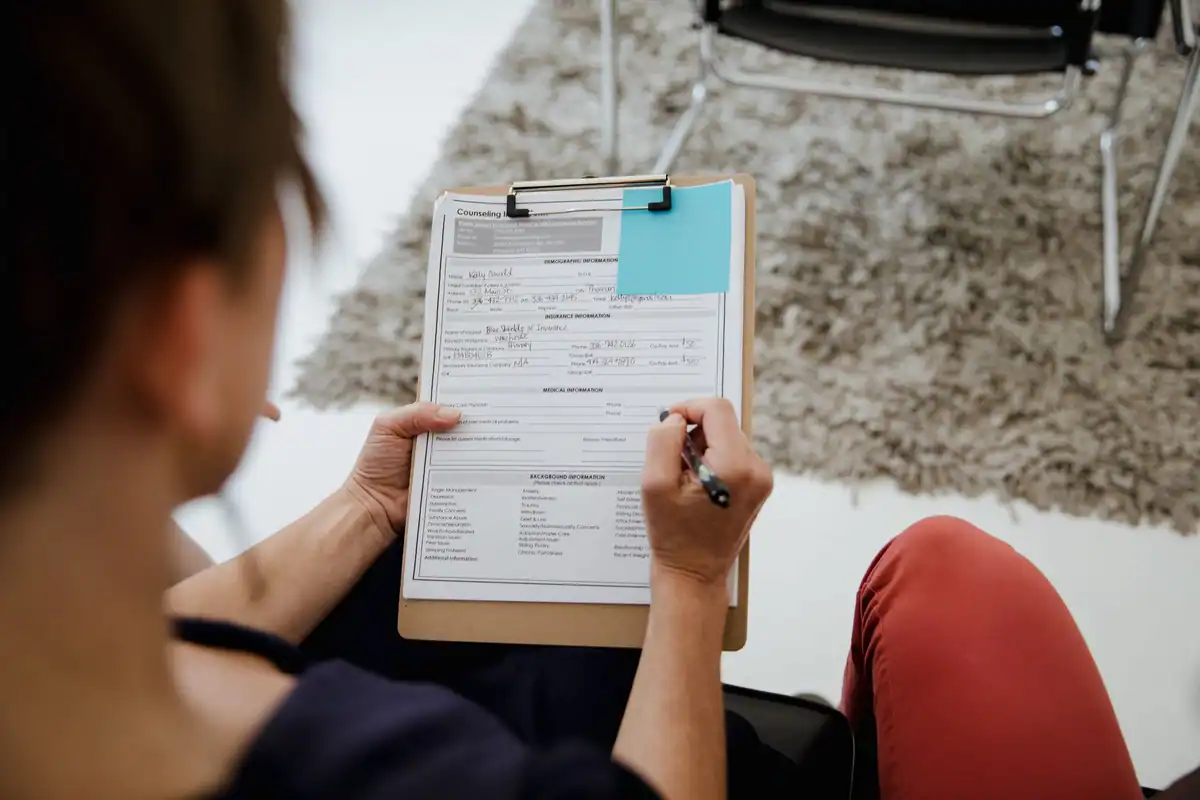 Femeie care completează un formular prins pe un clipboard
