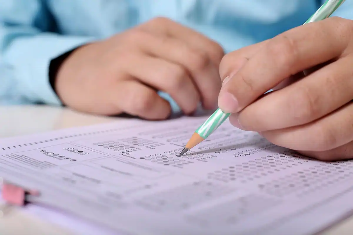 Mână care bifează cu creionul răspunsurile unui test grilă