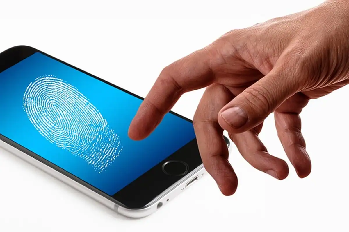 Deget care atinge ecranul unui telefon cu amprentă, pentru autentificare